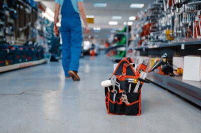 Toolbox in tool store, male worker in uniform on background. Choice of professional equipment in hardware shop, instrument supermarket